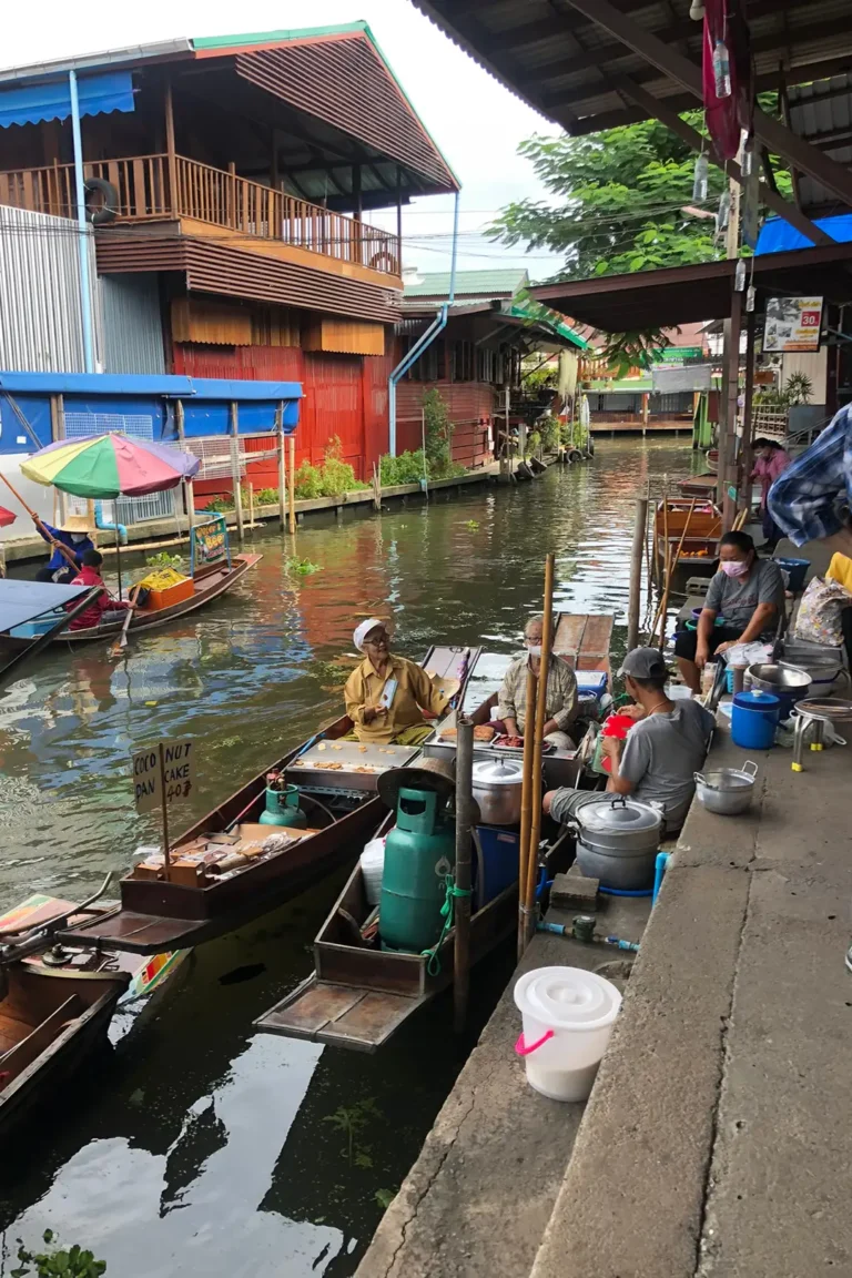 Bangkok et le Centre 14 Vendeurs de street food en barque préparant des galettes de coco au marché flottant traditionnel d'Amphawa