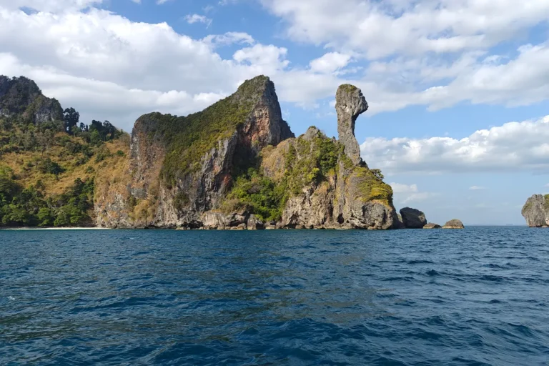 Formation rocheuse célèbre en forme de tête de poulet sur Chicken Island, baie d'Ao Nang, vue depuis la mer sous un ciel nuageux.