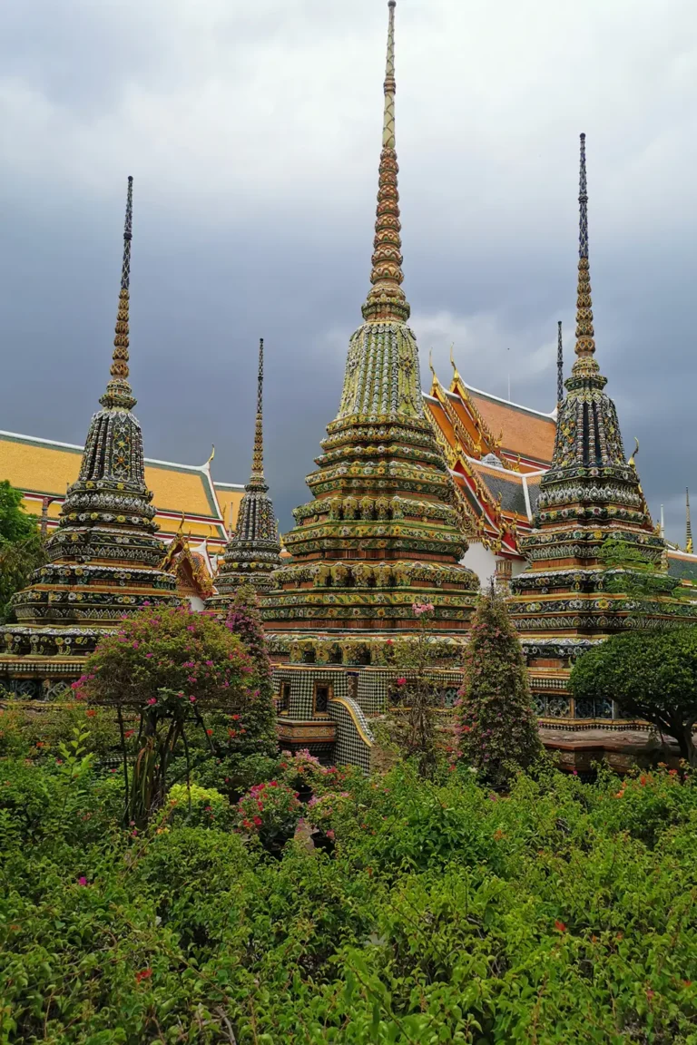 Bangkok et le Centre 4 Stupas en céramique du Wat Pho émergeant d'un jardin tropical fleuri sous un ciel d'orage à Bangkok