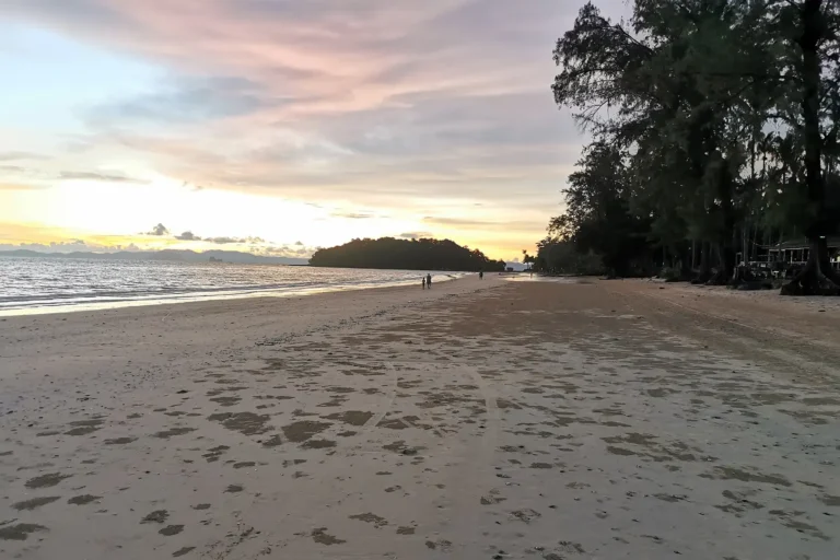 Plage de Klong Muang à la tombée de la nuit, sable fin et silhouette d'une île à l'horizon sous un ciel aux teintes pastel, Thaïlande.