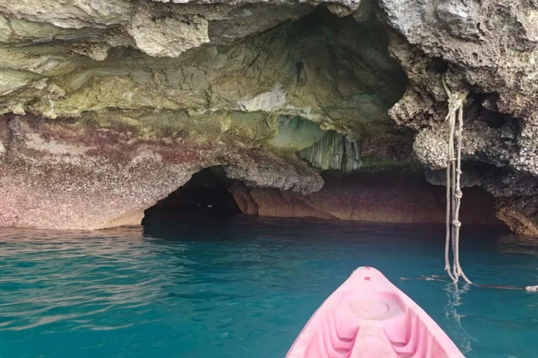 Kayak rose à l'entrée de la grotte d'Émeraude, eaux turquoise sous la voûte rocheuse de Koh Mook