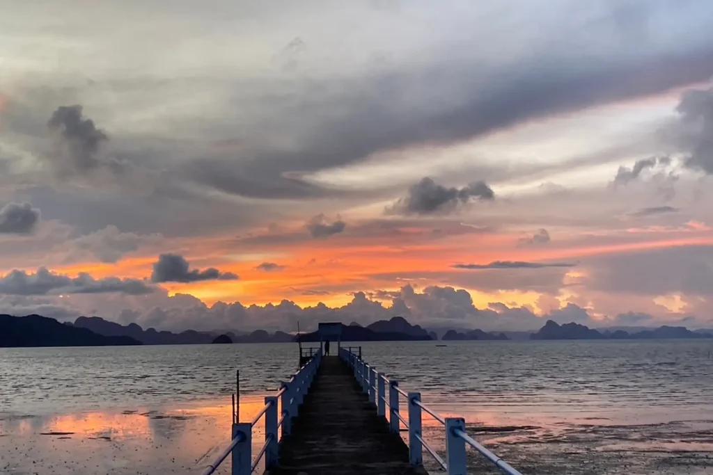 Coucher de soleil flamboyant depuis la jetée de Koh Yao Noi, silhouettes des pitons karstiques de la baie de Phang Nga