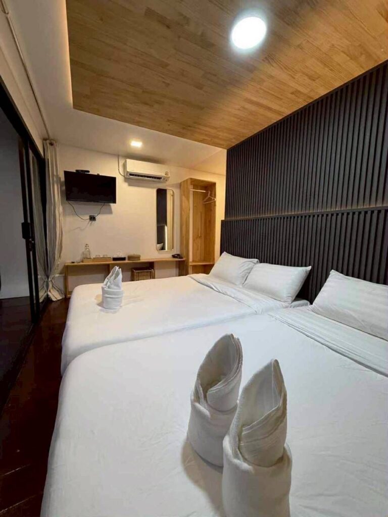 Intérieur d'une chambre luxueuse au complexe Phupha Waree, avec télé et climatisation, éclairée de nuit.