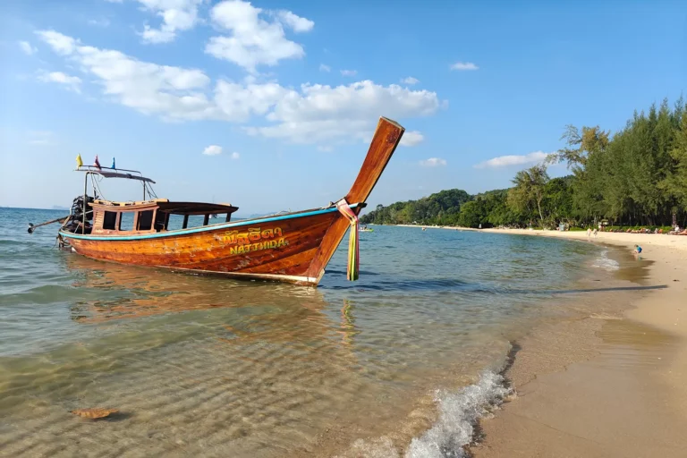 Bateau traditionnel à longue queue (Long-tail boat) stationné sur le rivage de la plage de Tubkaek avec vue sur l'archipel de Hong Islands.