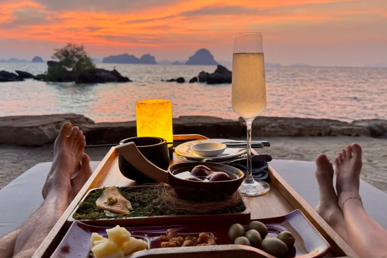 Expérience de dîner de luxe sur la plage de Tubkaek face au coucher du soleil, verre de champagne et cuisine raffinée avec vue sur mer.