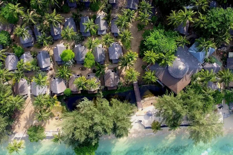 Essence du Sud 12 Vue aérienne de l'éco-resort Coco Cottage niché dans la végétation tropicale et les palmiers en bord de plage turquoise à Koh Ngai