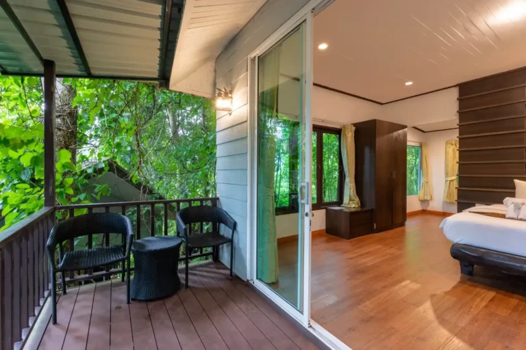 Essence du Sud 16 Terrasse privée en bois d'un bungalow Rock & Tree House avec fauteuils en rotin, ouverte sur la chambre et entourée de végétation tropicale, hébergement excursion Khao Sok