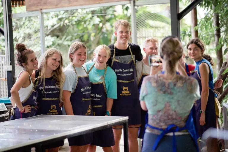 Cours de cuisine thaïlandaise 8 Groupe de jeunes voyageurs en tabliers Yaa's Thai Cookery School posant fièrement lors d'une activité cours de cuisine à Krabi, sud Thaïlande