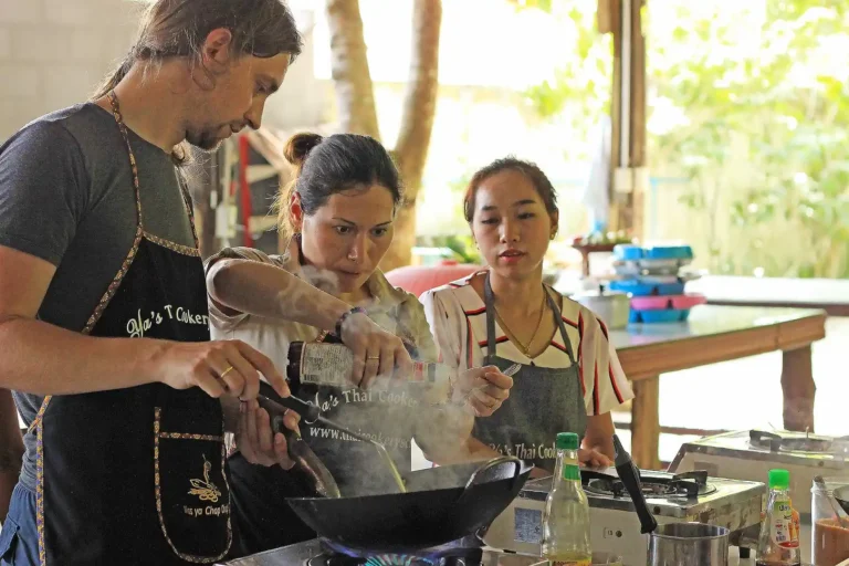 Cours de cuisine thaïlandaise 3 Participant apprenant à cuisiner au wok sous la guidance d'une instructrice thaïlandaise à l'école de cuisine de Yaa, Ao Nang Krabi