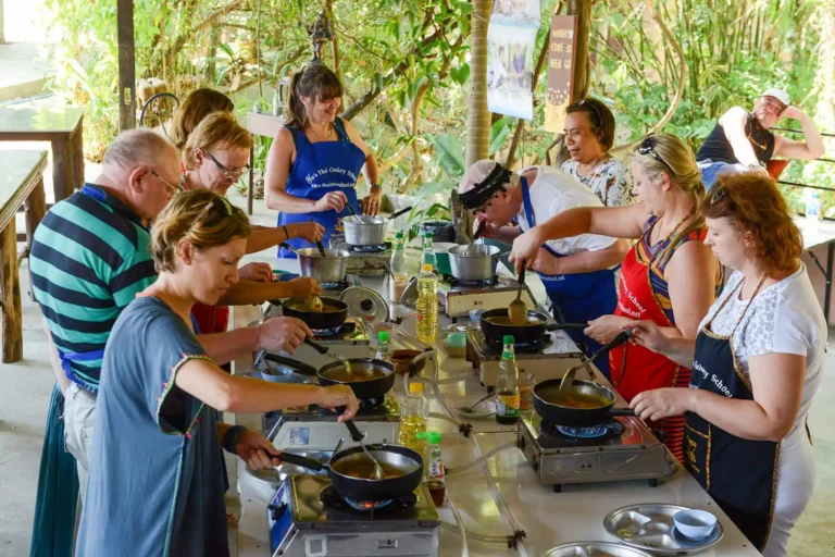 Cours de cuisine thaïlandaise 1 Grande tablée de participants cuisinant simultanément au cours de cuisine thaïlandaise de Yaa, activité Krabi en immersion culinaire
