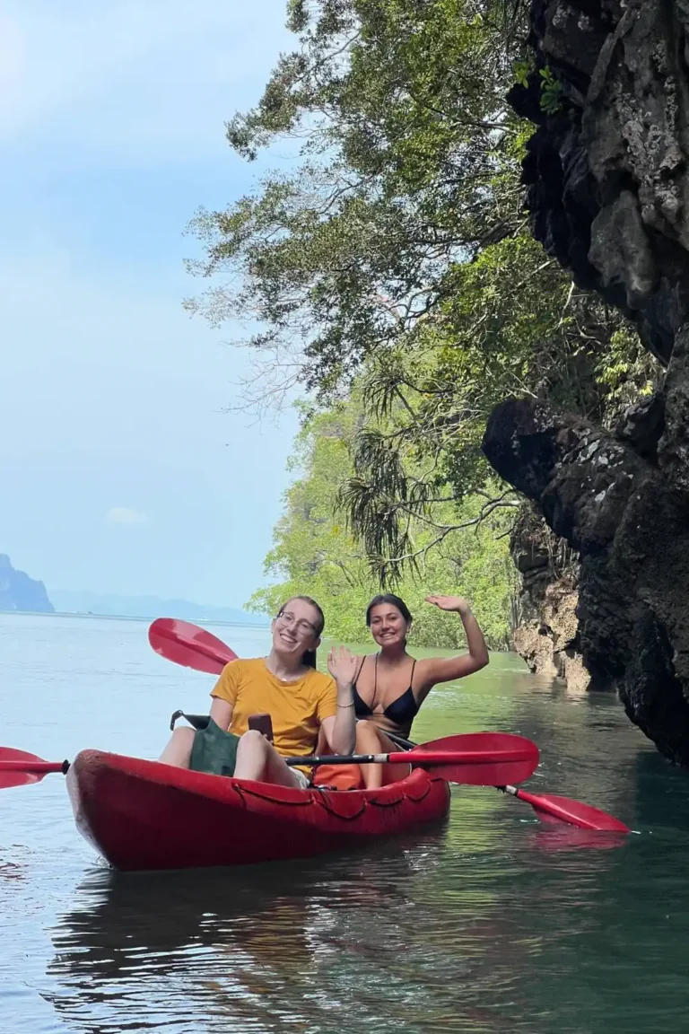 Deux amies souriantes en kayak rouge au pied d'une paroi rocheuse, excursion kayak Ao Thalane près de Krabi