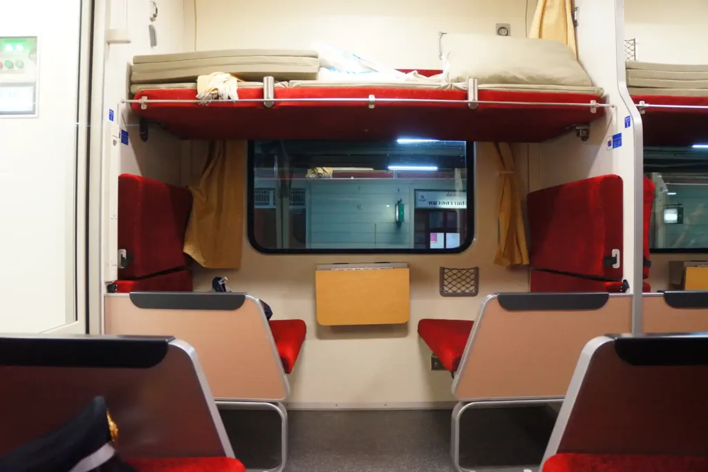 Compartiment de train de nuit en 2nde classe du réseau SRT en Thaïlande, avec banquettes rouges et couchette supérieure repliée